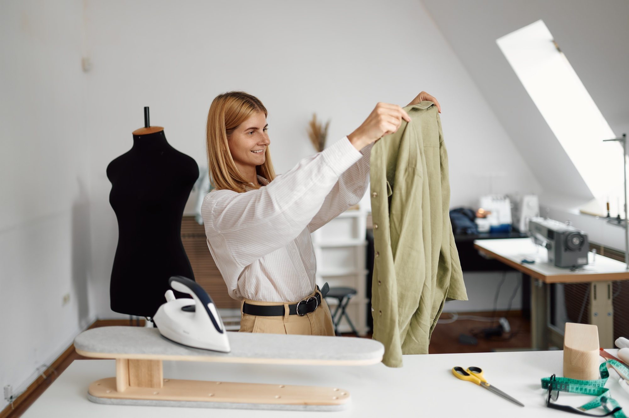 Seamstress looking on sewn dress in workshop